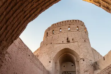 طاق خشتی که برجی کویری را در نور کم‌ارتفاع غروب قاب گرفته است