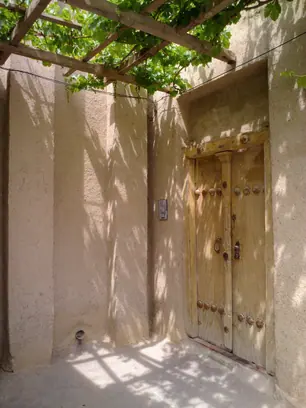 در چوبی کهنه در دیوار گچی، زیر سایهٔ داربست